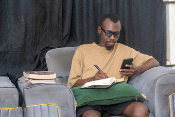 african man using cellphone to do his assignment