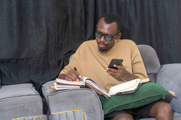 handsome african man using cellphone to do his assignment