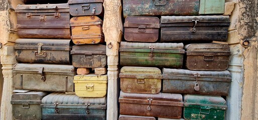 ollection of Aged and Corroded Iron Suitcases Stacked Neatly to Form a Decorative Background, Emphasizing the Patina, Rustic Colours, and Historical Aesthetic of Old Travel Gear