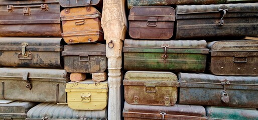 ollection of Aged and Corroded Iron Suitcases Stacked Neatly to Form a Decorative Background, Emphasizing the Patina, Rustic Colours, and Historical Aesthetic of Old Travel Gear