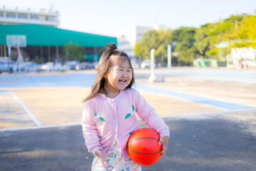 A cute little Asian girl is playing basketball on an outdoor court,Girl dribbling basketball - Offset Collection