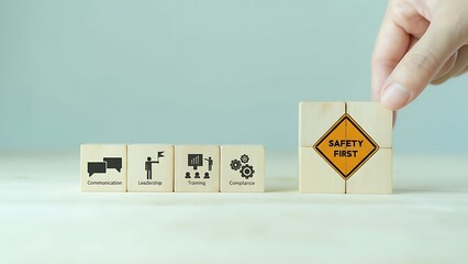 A hand places a Safety First block alongside other symbol blocks, highlighting workplace safety and communication.