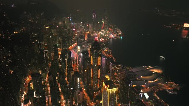 Aerial view of the vibrant, illuminated cityscapes, set against the dark harbor waters, creating a stunning contrast of light and shadow, Kowloon, Kowloon, Hong Kong.