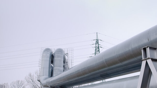 pipeline and power transmission tower against gray sky