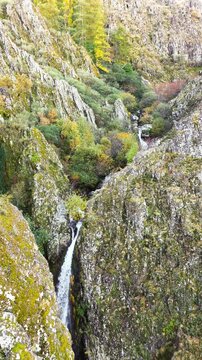 Aerial view of the Poco do Inferno waterfall cascading down the rugged, moss-covered cliffs, creating a stunning display of nature, Poco do Inferno, Manteigas, Portugal.