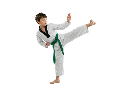 Young boy practicing high kick in martial arts uniform on white background