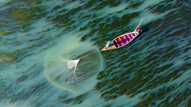 Rajshahi, Bangladesh - 15 December 2025: Aerial view of a small fishing boat with a net, casting a circular shadow on the water's surface.