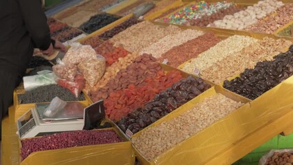 Vibrant Central Asian market counter showcasing mix of nuts, dried fruits, natural desserts and assorted organic products, displayed in large case designed to highlight freshness, quality and variety