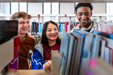 Multiethnic students finding books in library bookshelf