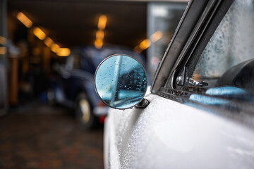Rain water droplets on a vintage car chromed, round, side mirror. Close up shot, shallow depth of field, no people