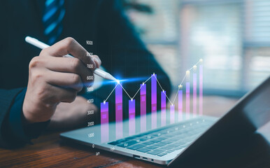 A person analyzing a digital bar and line chart on a laptop, highlighting monthly growth, financial performance, data analytics, and business strategy for investment and economic planning concepts.
