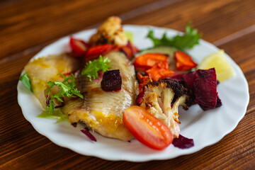 Baked fish with vegetables served on white plate