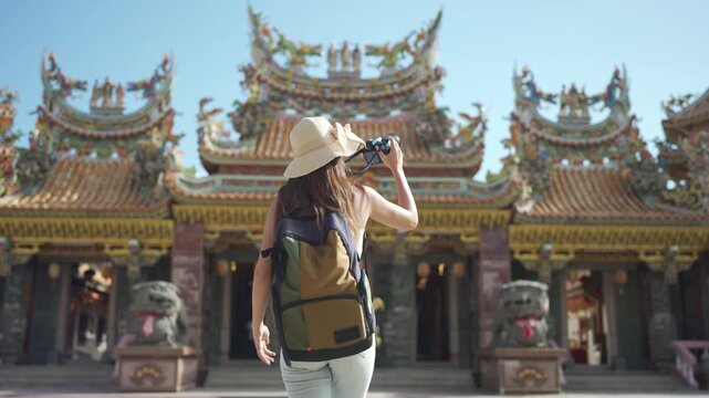 Female tourist walking around and taking photos inside a Chinese temple.