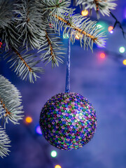 Colorful Sequined Ornament Hanging From Pine Branch With Christmas Lights
