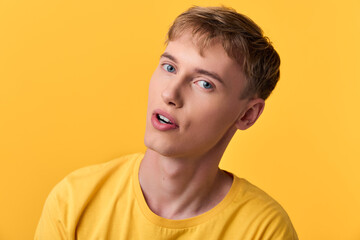 Closeup of a young man in a yellow shirt against a bright yellow backdrop, conveying a curious expression with a tilted head and vibrant color for a fresh, modern stock photography feel