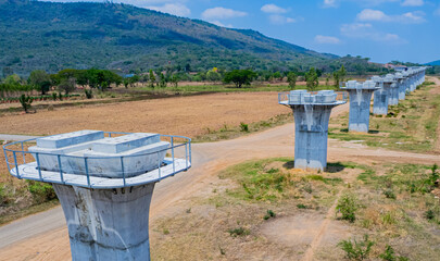 The concrete pillars/piers for the high-speed rail track are under construction at the unfinished construction site.