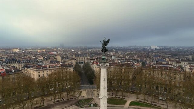 Drone pullback shot of Monument aux Girondins angel and Bordeaux skyline on moody overcast day