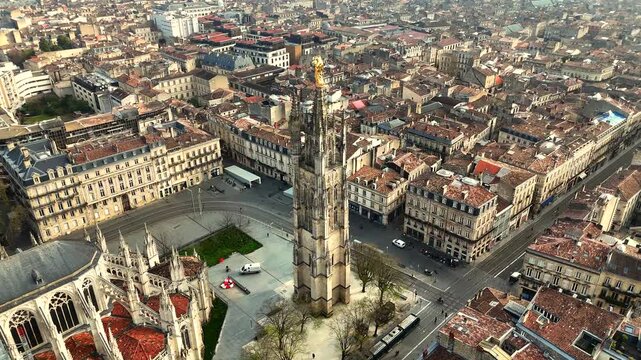Drone orbit shot of Saint-Michel Basilica and tall spire in Bordeaux on bright sunny day