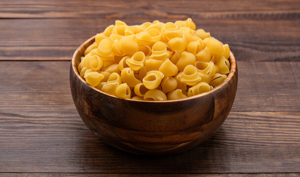 Raw pipe rigate pasta on wooden background