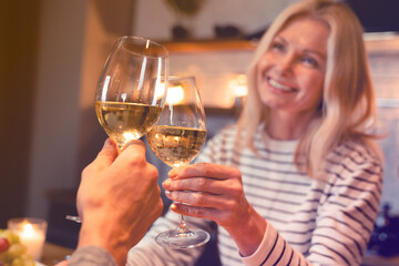 Focused photo of clinking glasses of wine with happy couple on the background during romantic date. Relationship and love. Celebration special event concept