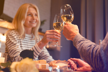 Focused photo of clinking wine glasses of happy beautiful couple on a romantic date. Cheering while drinking champagne alcoholic beverage dining proposal celebration.