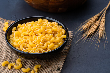 Raw macaroni pasta on black stone background