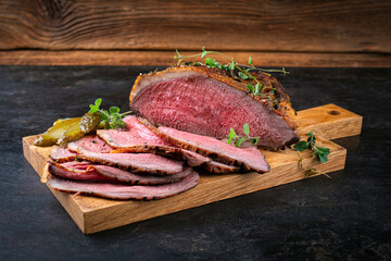 Traditional Commonwealth Sunday roast with sliced cold cuts roast beef served as close-up on a wooden cutting board