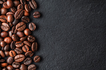 Roasted coffee beans border on dark slate