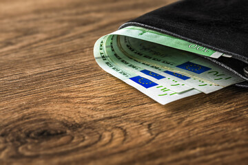 Euro banknotes in wallet on wooden table