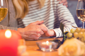 Close up shot of happy couple holding hands together on a romantic dinner table. Physical touch - love language. Tenderness in gestures. St Valentine`s Day, proposal, anniversary celebration