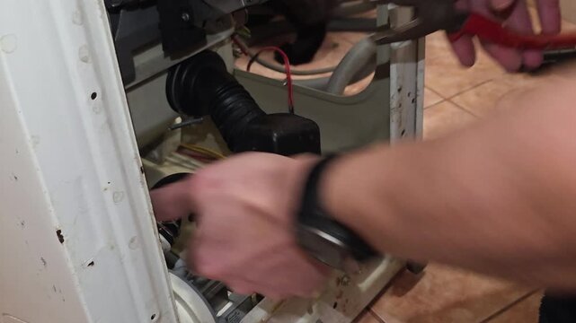 Man repair washing machine pipes with pliers and wrench, home appliance maintenance and plumbing work in progress for broken household equipment