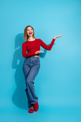 Beautiful young woman in casual red top and jeans posing with a cheerful gesture against a vibrant...