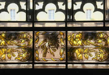 Detailed view of stained glass with golden decorative motifs and geometric framing.