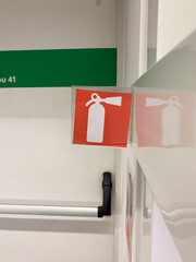 Red fire extinguisher symbol on wall reflecting on mirror