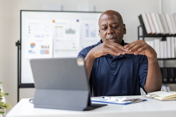 Senior manager working with documents and tablet in office. He is stressed and worried.