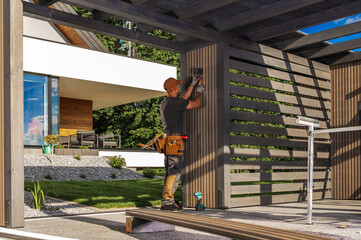 Worker Builds Wooden Structure in Outdoor Space