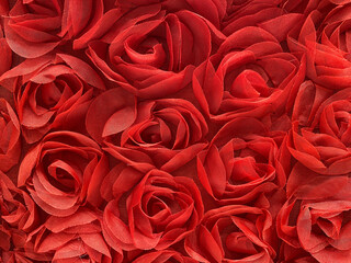 Vibrant red fabric roses tightly arranged in a textured pattern