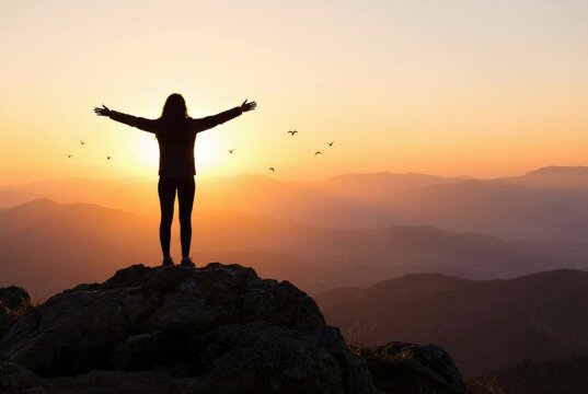 Person enjoying sunset on a mountain with arms outstretched.