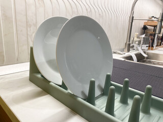 White plates drying on kitchen counter in dish rack near sink