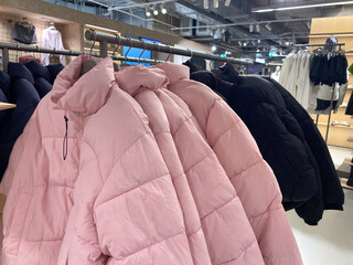 Winter jackets hanging in clothing store display with pink and black coats