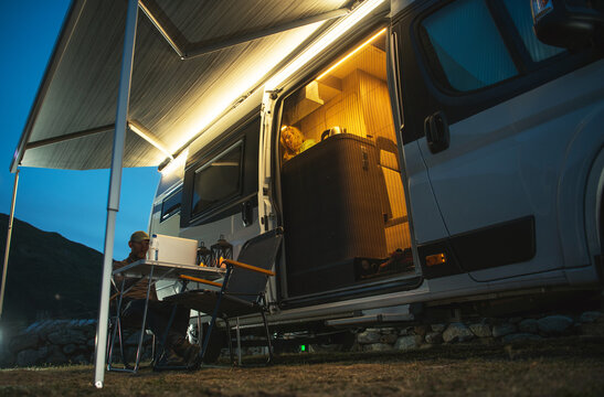 Computer Working at Night Near a Camper Van With Light On