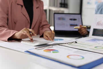 Business team analyzing financial data and company's performance using calculator and documents.