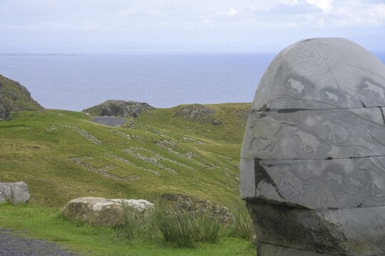 Stone monument with animal representations in the background Eire sign, on the way to the Slieve League cliffs, West Donegal, County Donegal, Ireland
