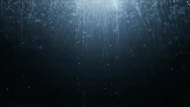 Showing curtain of falling water, rain starting and streaming down at night, backlighting droplets