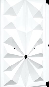 A close-up showcases a bright white surface with geometric shapes and sharp angles, with a black backdrop