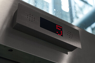 Modern elevator display showing floor number five in red digits