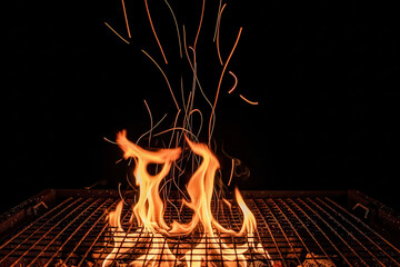 Barbecue grill embers with flames and sparks on charcoal, dark fire background