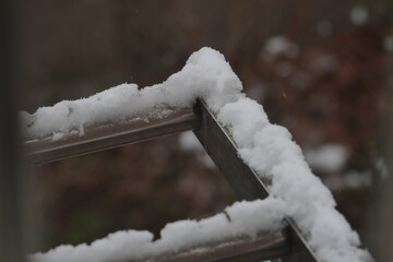 A close-up shot of thick, fresh snow resting on the metal railing of an outdoor structure during a snowy day.