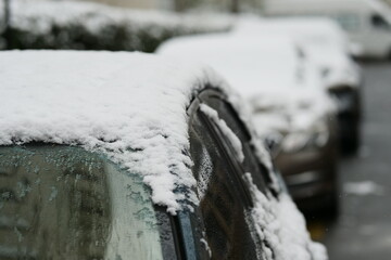A close-up shot of a car heavily covered in fresh, wet snow on a winter day.