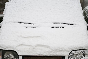 A close-up shot of a car heavily covered in fresh, wet snow on a winter day.